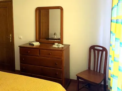 a bedroom with a dresser and a mirror and a chair at Casa do Cisne in Porto Santo