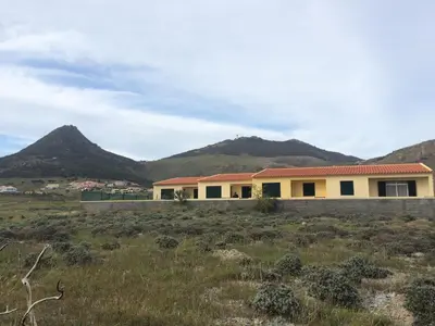 a house in a field with mountains in the background at Cantinho Solpraia in Porto Santo