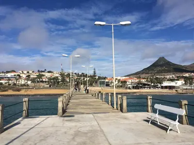 a pier with a bench and street lights next to the water at Cantinho Solpraia in Porto Santo