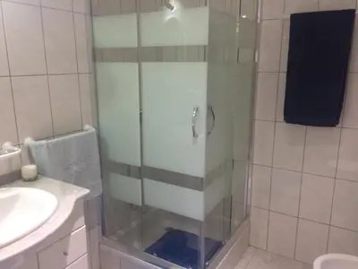 a shower with a glass door next to a sink at Cantinho Solpraia in Porto Santo