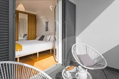 a bedroom with a bed and two chairs on a balcony at Barreiros I by An Island Apart in Funchal