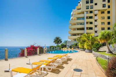 a swimming pool with lounge chairs and a building at The Cliff Side Apartment in Funchal