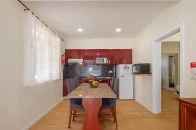 a kitchen with red cabinets and a table with a bowl of fruit at Cantinho das Feiteiras by Homie in São Vicente