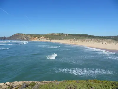 a view of a beach with a wave in the water at Moradia Vale da Telha in Aljezur