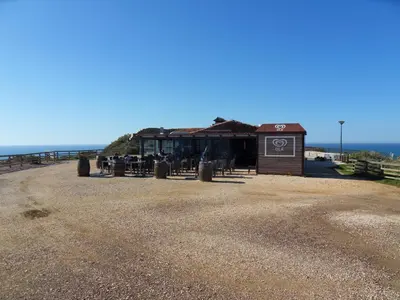 a building on the beach with the ocean in the background at Moradia Vale da Telha in Aljezur
