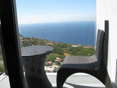 a chair sitting on a balcony looking out at the ocean at Villa Girasol in Arco da Calheta
