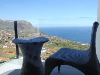 a chair sitting on top of a balcony overlooking the ocean at Villa Girasol in Arco da Calheta