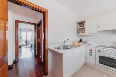 a kitchen with white cabinets and a sink at Funchal Lounge Apartment by Amazing Madeira in Funchal