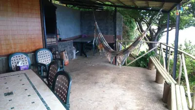 a porch with chairs and a hammock on a house at Ocean View Cottage in Arco da Calheta
