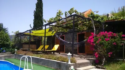 a house with a yellow umbrella and a pool at Ocean View Cottage in Arco da Calheta