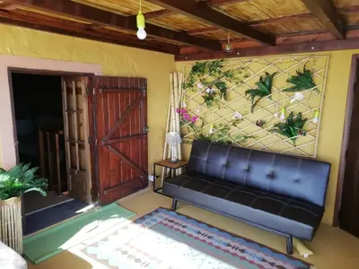 a living room with a black couch and a painting on the wall at Ocean View Cottage in Arco da Calheta