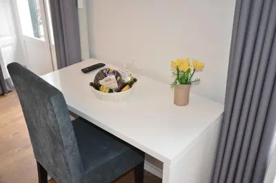 a white table with a basket of flowers and a vase at Edificio Charles 103 in Funchal