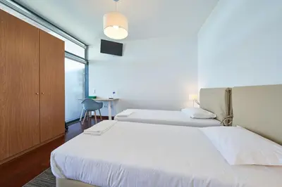 a bedroom with two beds and a large window at Marina Rooms in Calheta