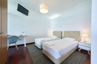 a hotel room with two beds and a desk at Marina Rooms in Calheta