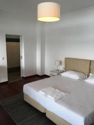 a bedroom with a large white bed with a light at Marina Rooms in Calheta