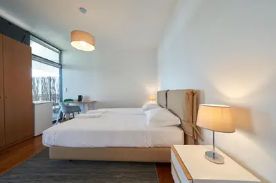 a bedroom with a bed and a table with a lamp at Marina Rooms in Calheta