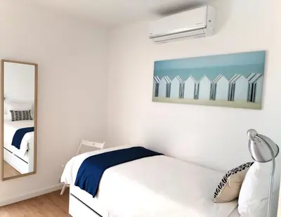 a white bedroom with a bed and a mirror at Porto Santo - Pedras Pretas Beach House in Porto Santo