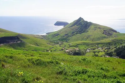 a view of a green hill with the ocean in the background at Porto Santo - Pedras Pretas Beach House in Porto Santo