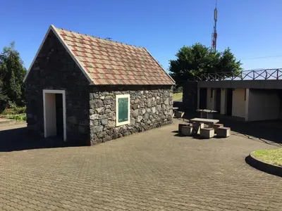 a small stone building with a picnic table and benches at Casa da Grota in Porto Moniz