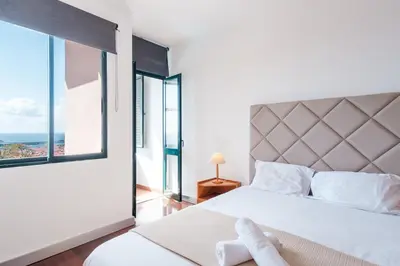 a bedroom with a large bed with a large window at Varandas Funchal-Near center in Funchal