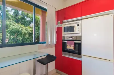 a kitchen with a red wall and a microwave at Varandas Funchal-Near center in Funchal