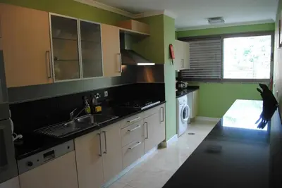 a kitchen with green walls and white cabinets at Plaza Bay Luxury Apartment with Swimming Pool in Estreito da Calheta