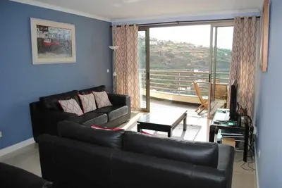 a living room with a couch and a large window at Plaza Bay Luxury Apartment with Swimming Pool in Estreito da Calheta