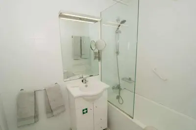 a white bathroom with a sink and a shower at Cliff View III - Sea View + Pool + Wifi in Funchal