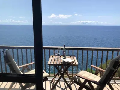 a table and chairs on a balcony with the ocean at Cliff View III - Sea View + Pool + Wifi in Funchal