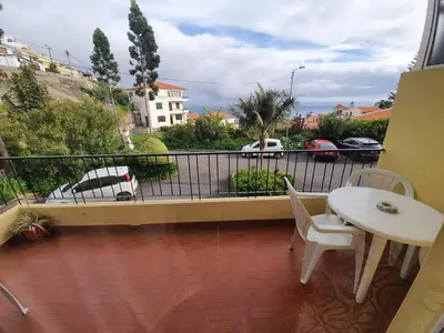 a balcony with a table and chairs and a view of a parking lot at Inmaculado Apartment in Funchal