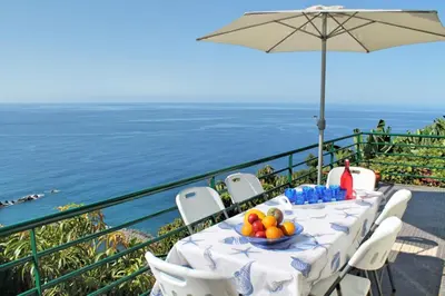 a table with a bowl of fruit sitting on a balcony at OurMadeira - Casa Jardim Mar in Ponta do Sol