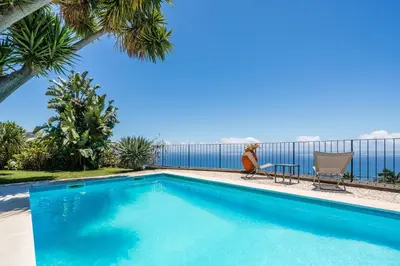 a woman sitting in a chair next to a swimming pool at OurMadeira - Quinta D'Alegria in Funchal