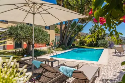 a pool with chairs and an umbrella next to a building at OurMadeira - Quinta D'Alegria in Funchal