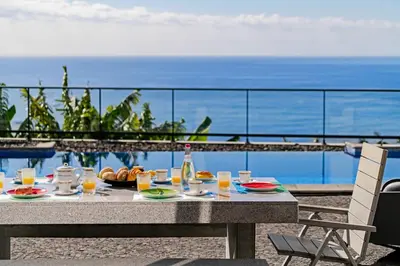 a table with food and drinks and a view of the ocean at OurMadeira - Grayci's House in Arco da Calheta