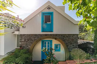 a house with a blue door and a stone wall at OurMadeira - Villa do Mar II in Arco da Calheta