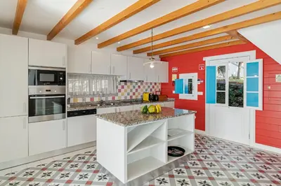 a kitchen with white cabinets and a red wall at OurMadeira - Villa do Mar II in Arco da Calheta