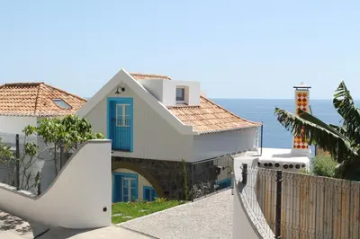 a white house with a blue door and the ocean at OurMadeira - Villa do Mar II in Arco da Calheta