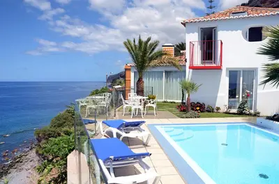 a house with a swimming pool next to the ocean at OurMadeira - Villa do Mar II in Arco da Calheta