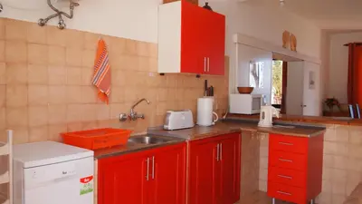 a kitchen with red cabinets and a sink at OurMadeira - Villa Mary in Porto Santo