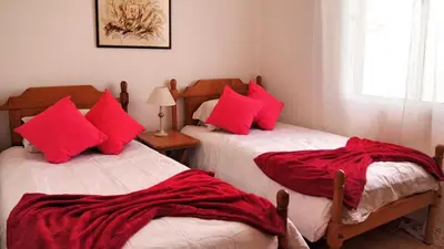 two beds in a room with red pillows at OurMadeira - Villa Mary in Porto Santo