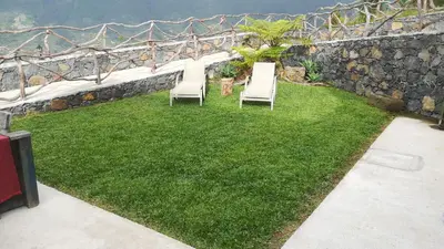 two chairs sitting on the grass next to a stone wall at Refúgio da Xamusca in São Vicente