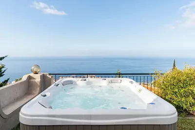 a hot tub on a balcony with the ocean in the background at Vila Eucalipto by An Island Apart in Funchal