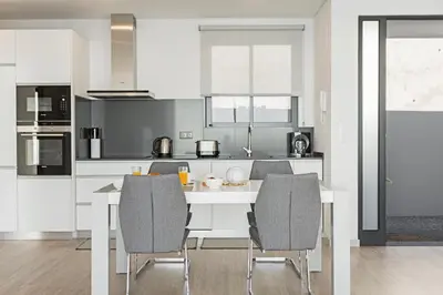 a kitchen with a white table and chairs at Searenity Vacation Home I by An Island Apart in Arco da Calheta