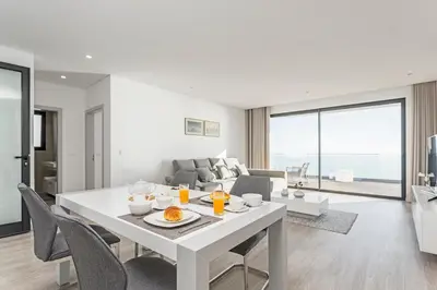 a white dining room with a white table and chairs at Searenity Vacation Home I by An Island Apart in Arco da Calheta