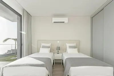 two beds in a white room with a window at Searenity Vacation Home II by An Island Apart in Arco da Calheta