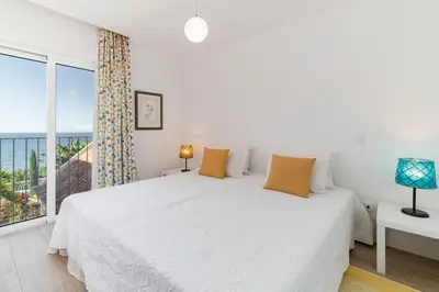 a white bedroom with a large bed and a window at OurMadeira - Villa do Mar III in Arco da Calheta