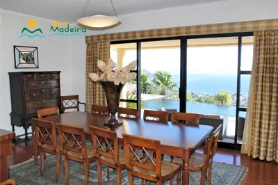 a dining room with a table and chairs with a view of the ocean at OurMadeira - Villa Luz in Funchal