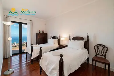 two beds in a room with a view of the ocean at OurMadeira - Villa Luz in Funchal
