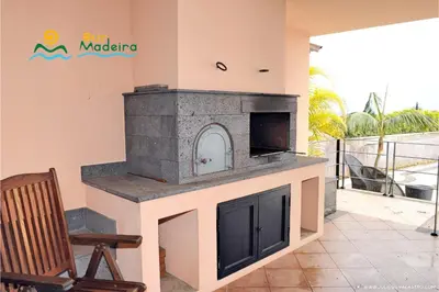 a stone fireplace in a patio with a chair at OurMadeira - Villa Luz in Funchal