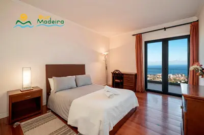 a bedroom with a bed with a view of the ocean at OurMadeira - Villa Luz in Funchal